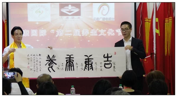 中华五环养生长寿功首次出川 陈红涛教授赴云南传授健康功法(图2) 开幕式上,陈红涛教授向吉康国际总裁邱光全赠送国家一级书法家姬长轩“吉康康养”书法作品